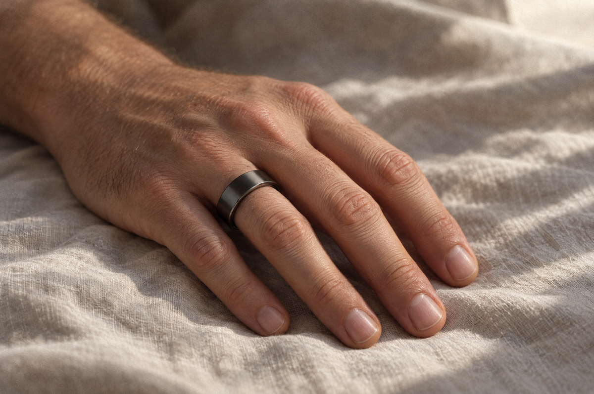 A hand resting on linen wearing the PulseRing Pro on the index finger