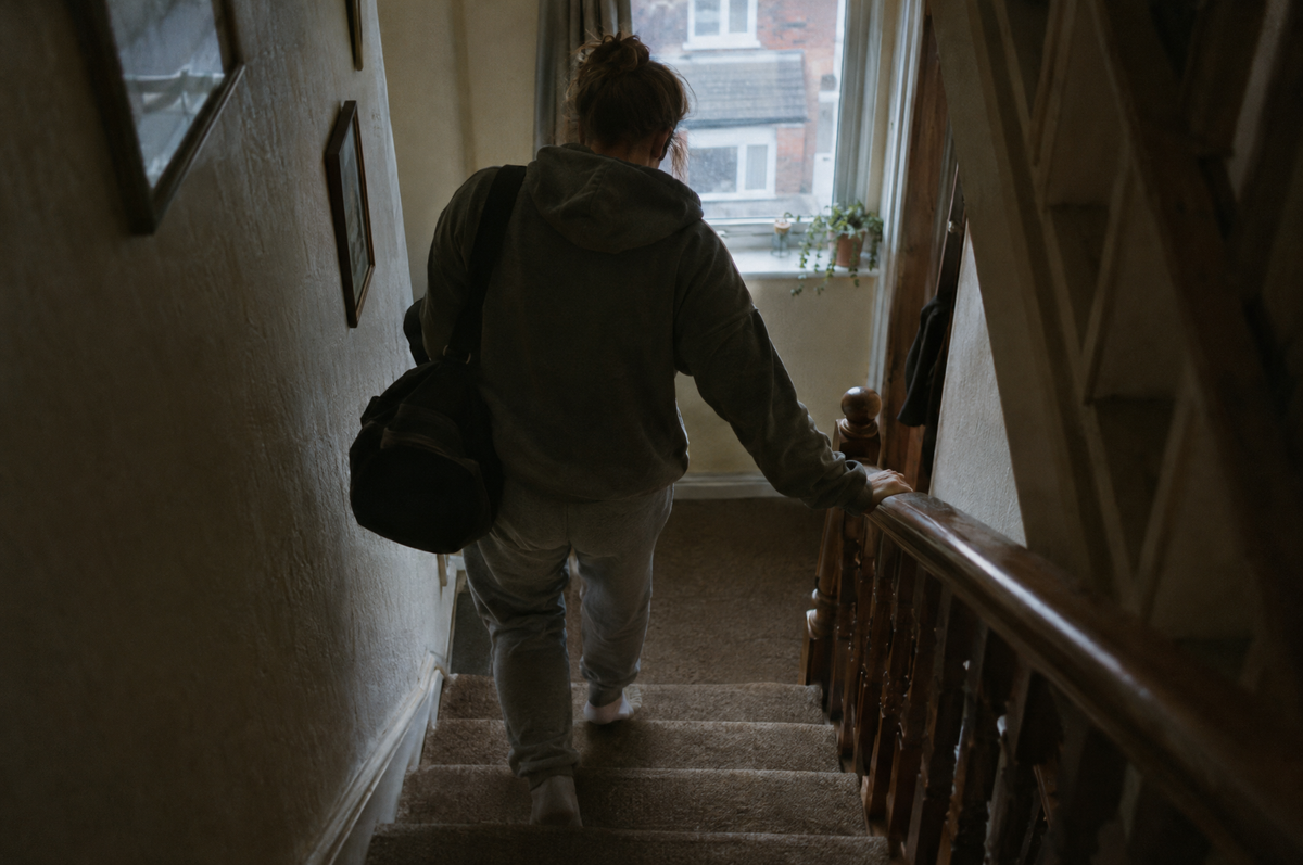Someone walking stiffly down the stairs holding the banister the morning after leg day
