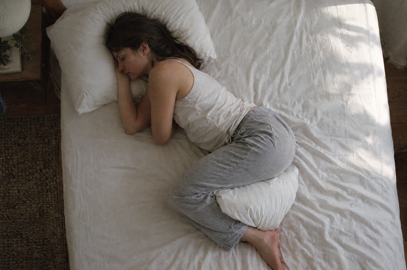 A woman sleeping on her side with a pillow between her knees